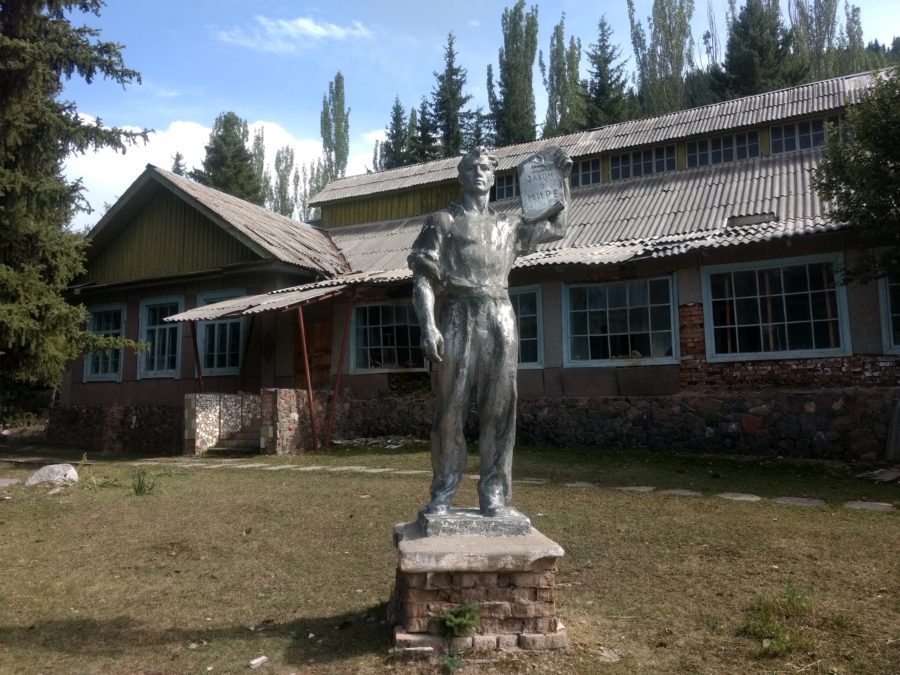 Soviet worker statue in front of building with broken windows at Jeti-Oguz sanatorium